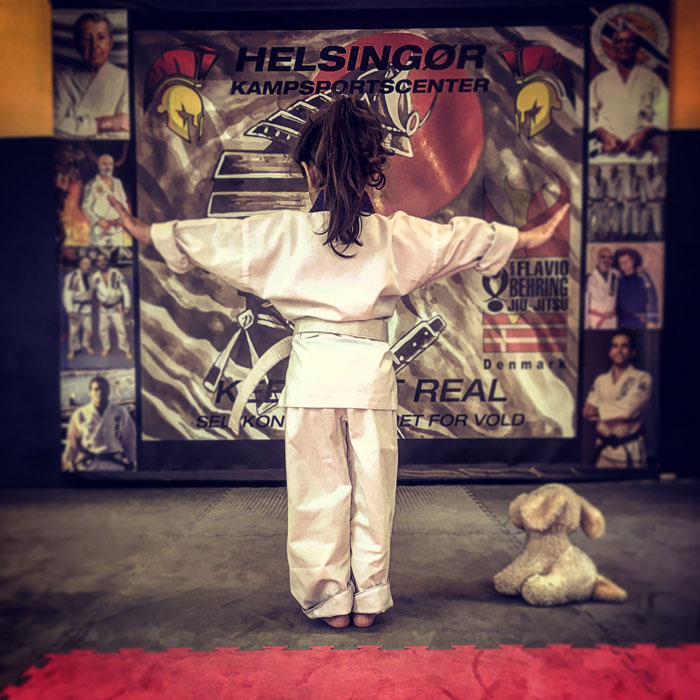 Billedet viser en Kung Fu pige i sin hvide dragt klar til kamp med sin søde bamse hund